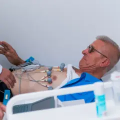 Mężczyzna z elektrodami EKG na klatce piersiowej, pod opieką lekarzy, w stanie przedzawałowym.