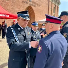 Uroczystość wręczenia medalu za zasługi dla pożarnictwa. Strażak w mundurze otrzymuje odznaczenie.