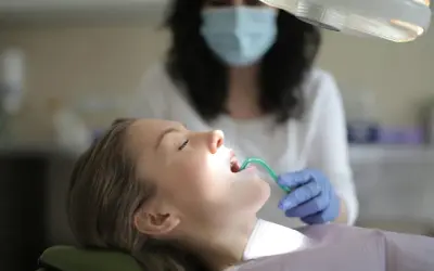 Pacjentka u dentysty, która ma otwarte usta i zielony przyrząd w jamie ustnej.