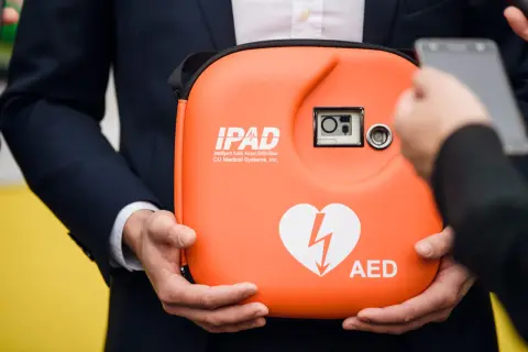 Pomarańczowy AED w etui, z sercem i błyskawicą. Zastanawiasz się, ile kosztuje AED?