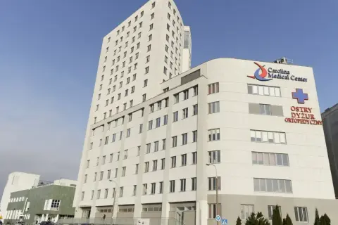 Nowoczesny budynek Carolina Medical Center w Warszawie z niebieskim krzyżem i napisem "Ostry Dyżur Ortopedyczny".