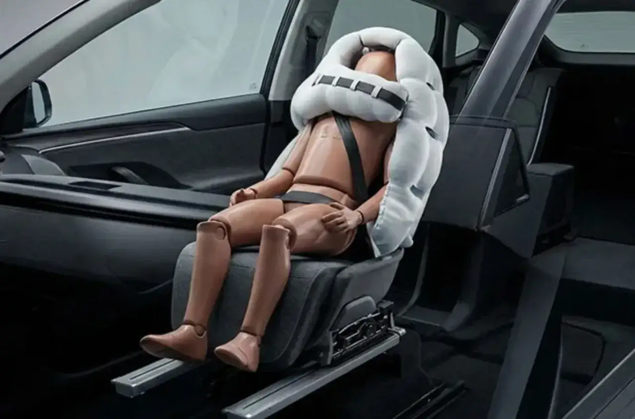 Manekin w samochodzie otoczony przez nadmuchany airbag, gotowy do testu bezpieczeństwa.